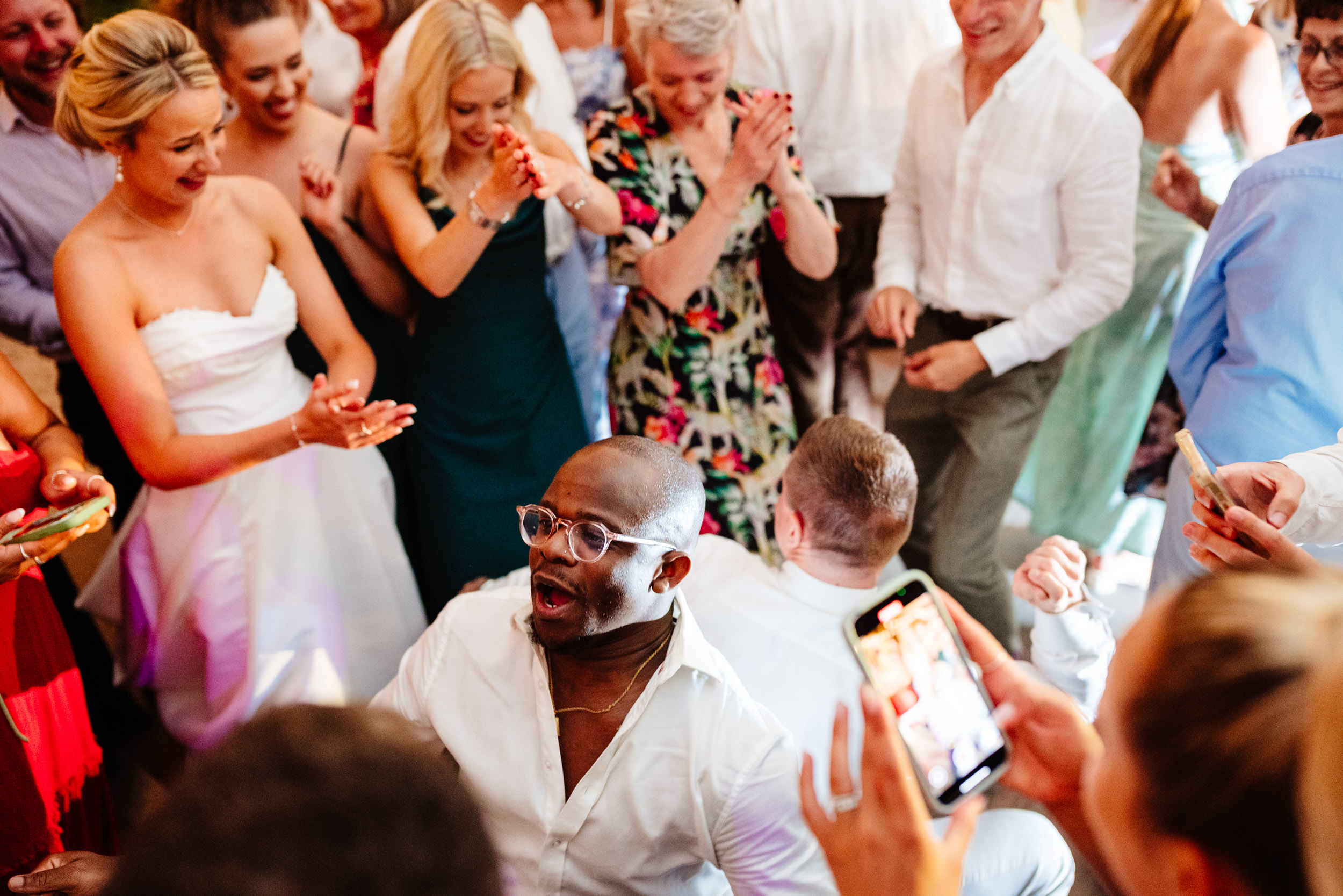 Wedding guests dancing wildly on the dance floor while being filmed on a phone