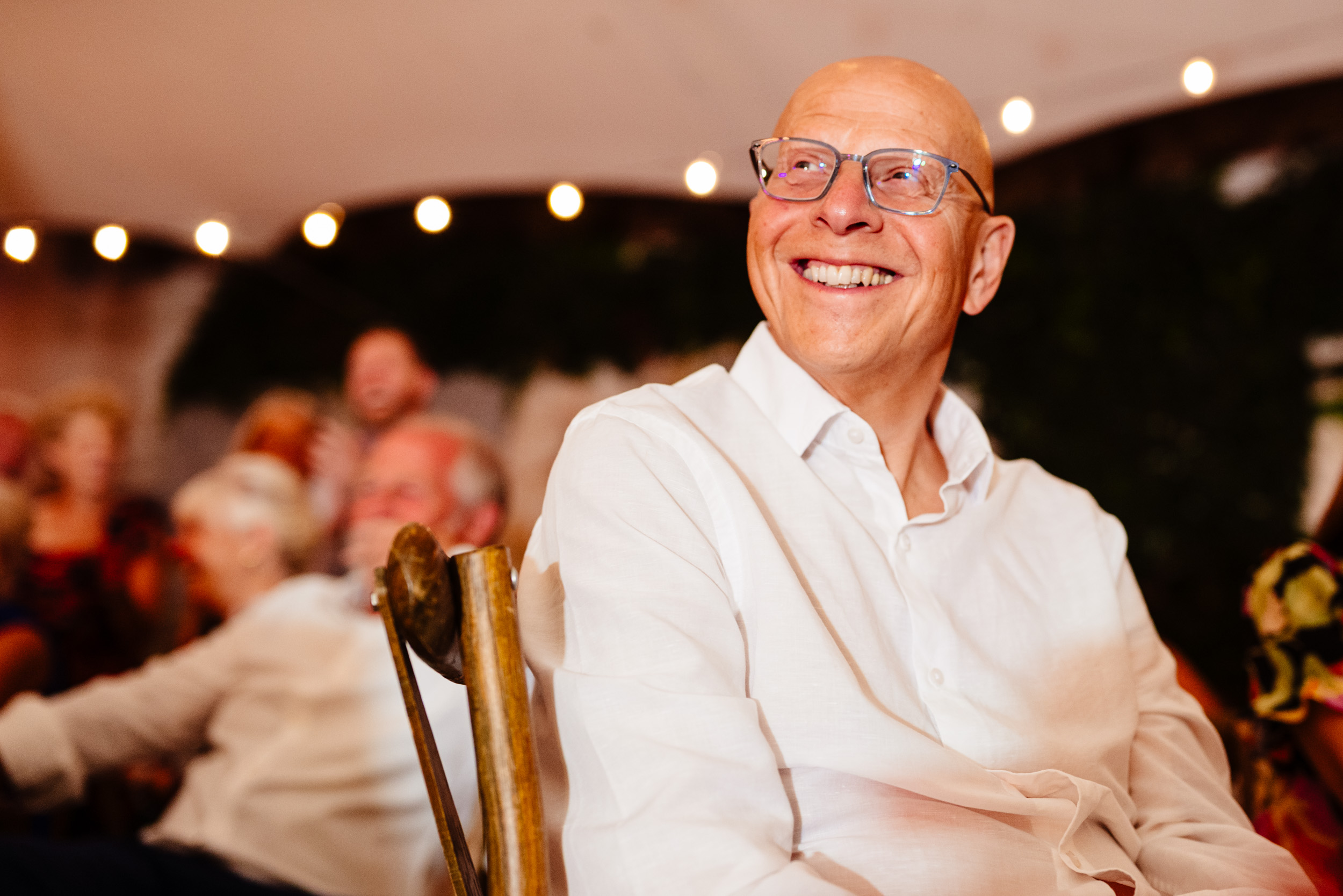 Wedding guest sitting and laughing while watching the dance floor