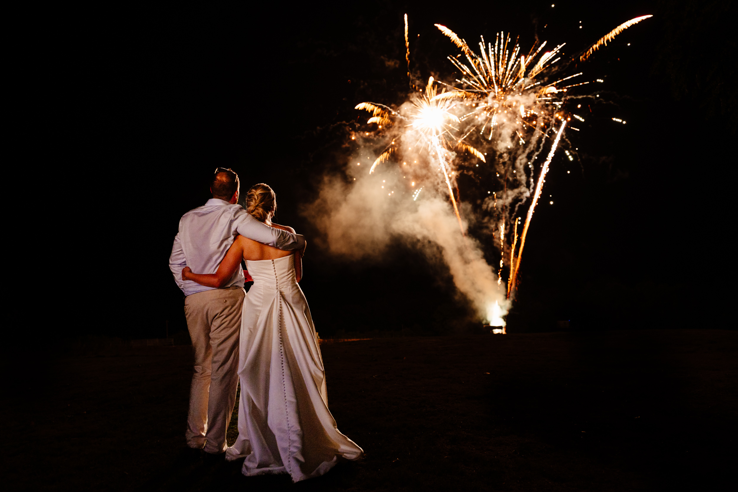 Bride and groom watching fireworks together at their wedding