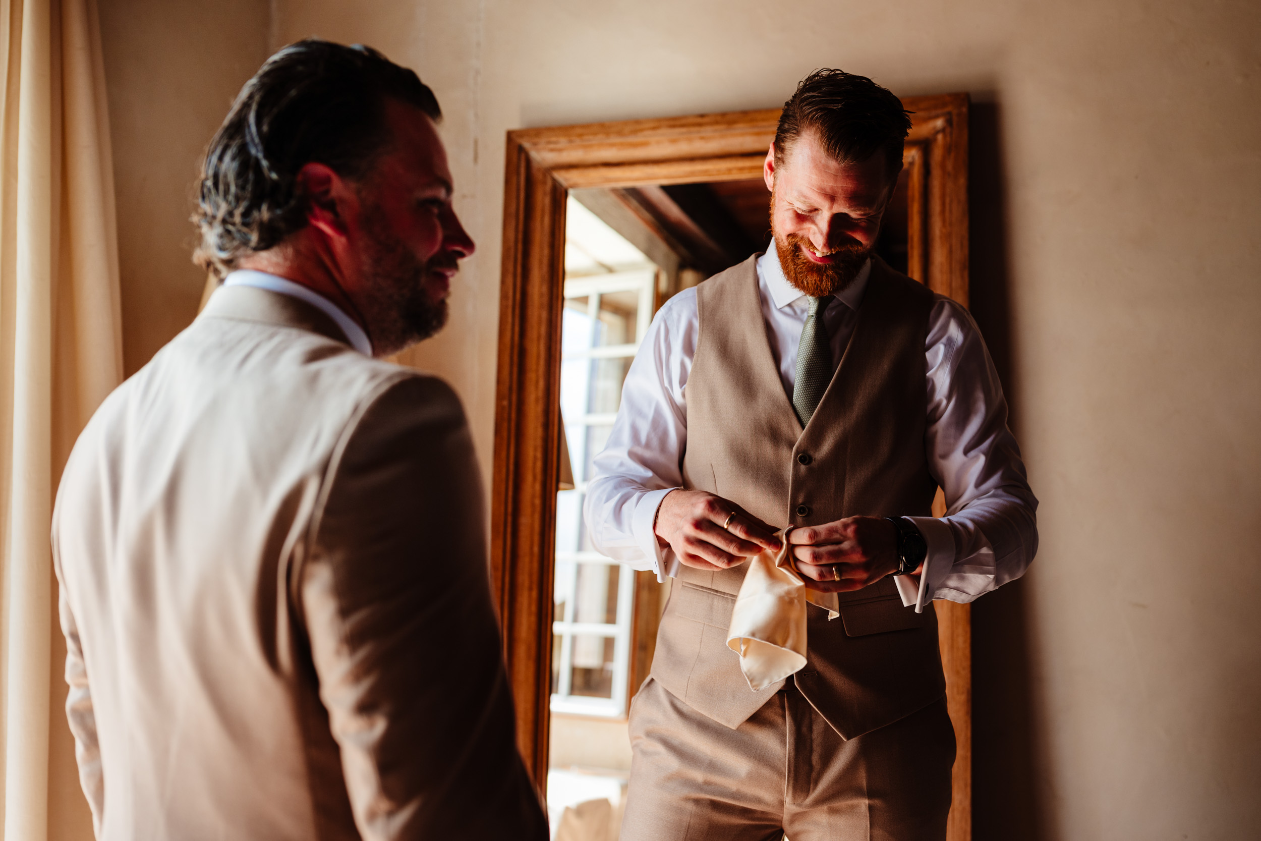 Best man adjusting his handkerchief with groomsmen during morning preparations