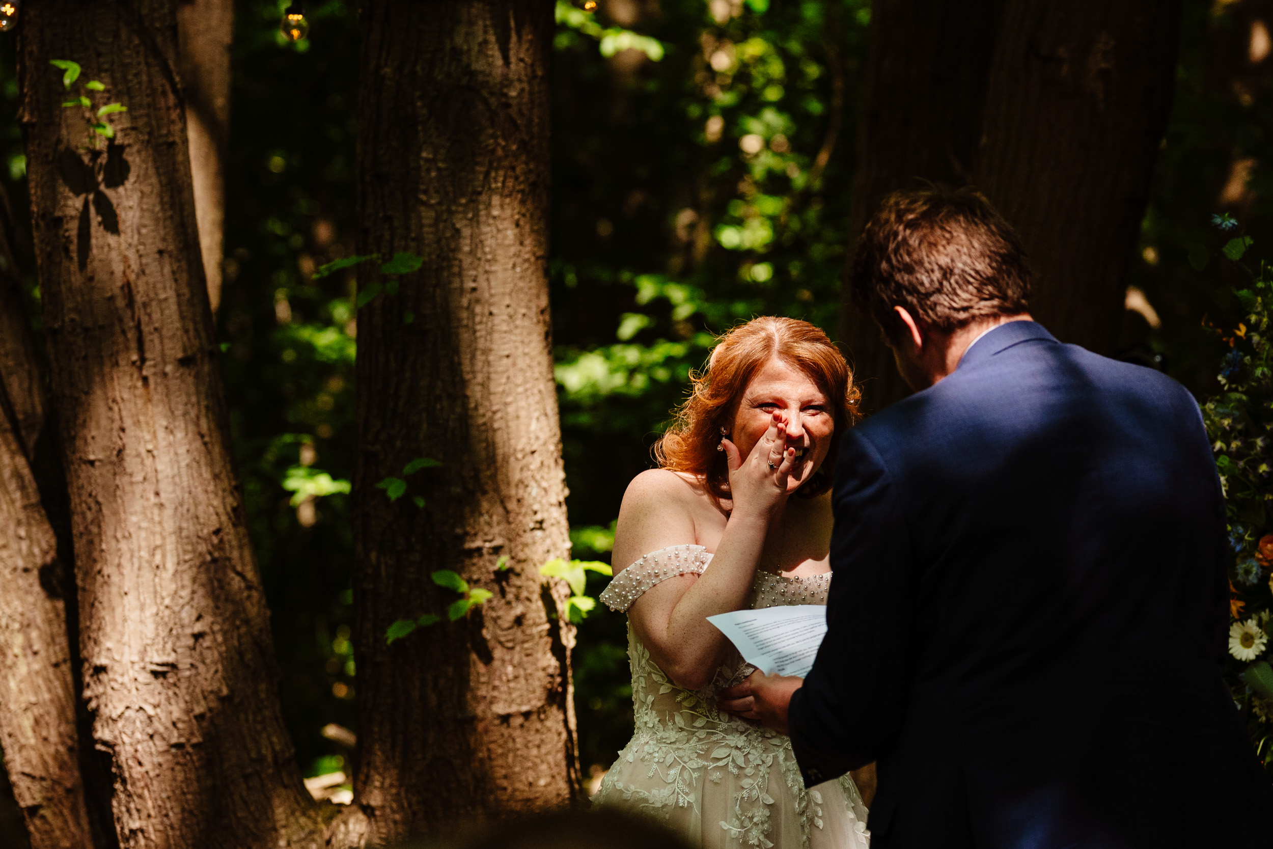 Bride smiling at the groom in soft, dappled light during the ceremony
