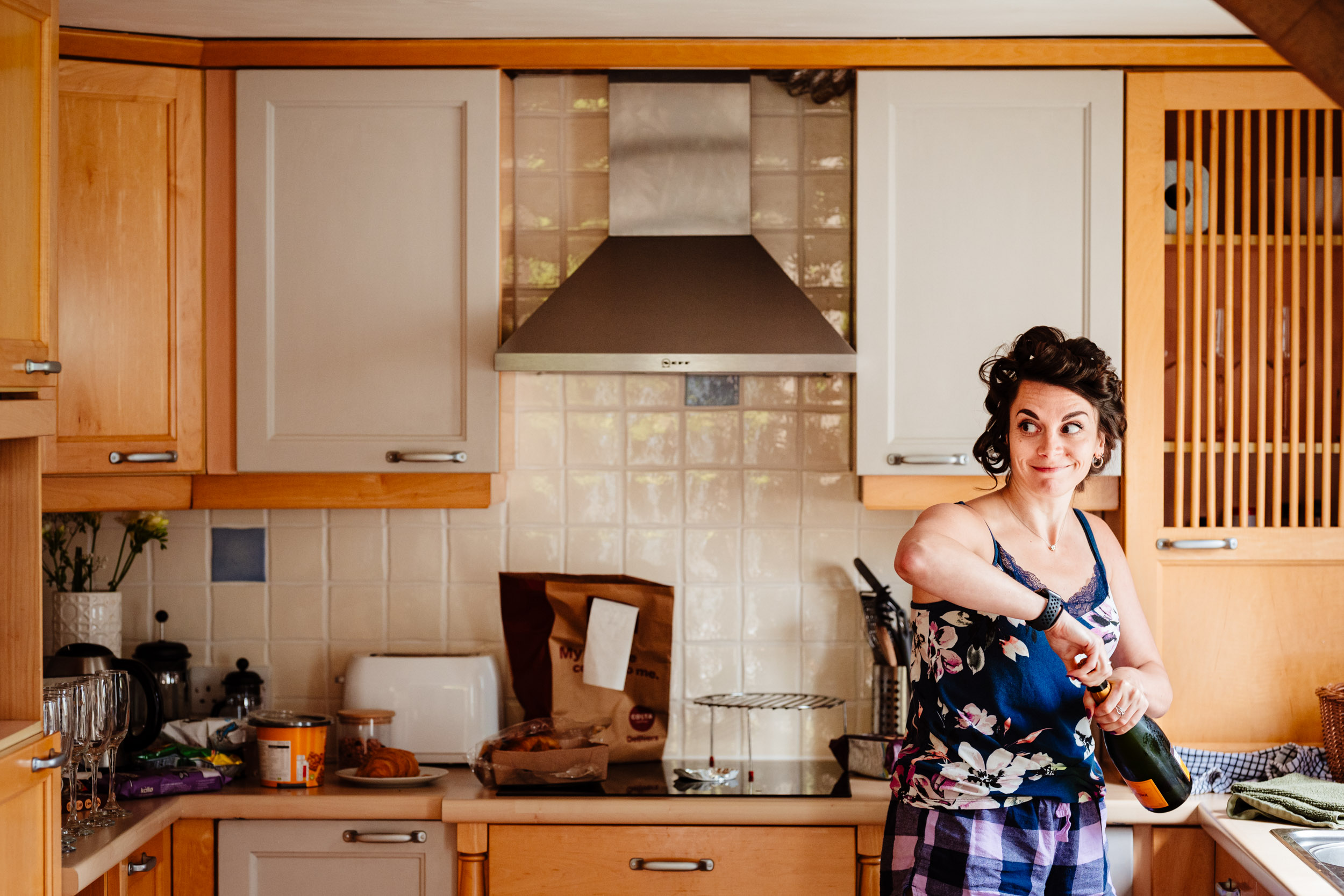 Bridesmaid about to pop a champagne bottle during relaxed wedding morning preparations