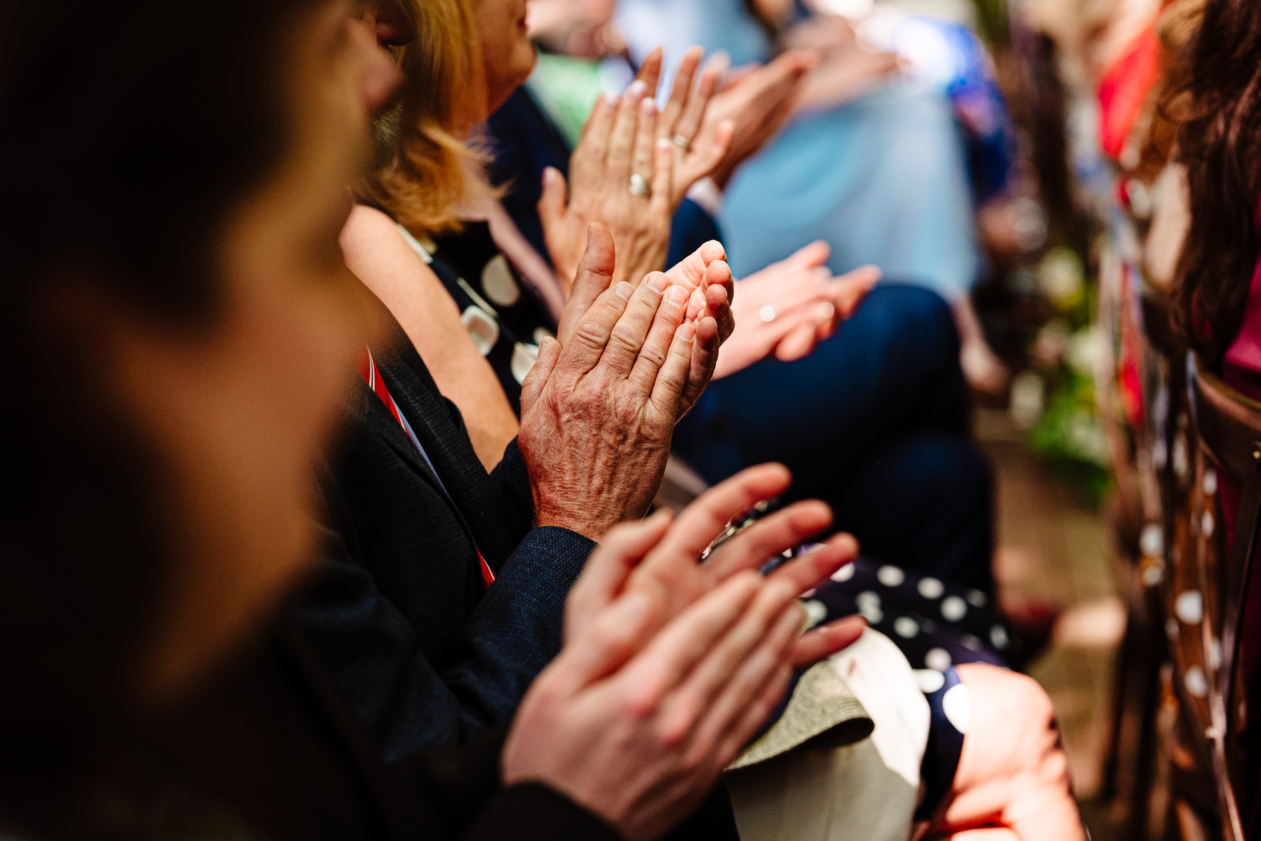 Close-up of wedding guests’ hands clapping during the ceremony
