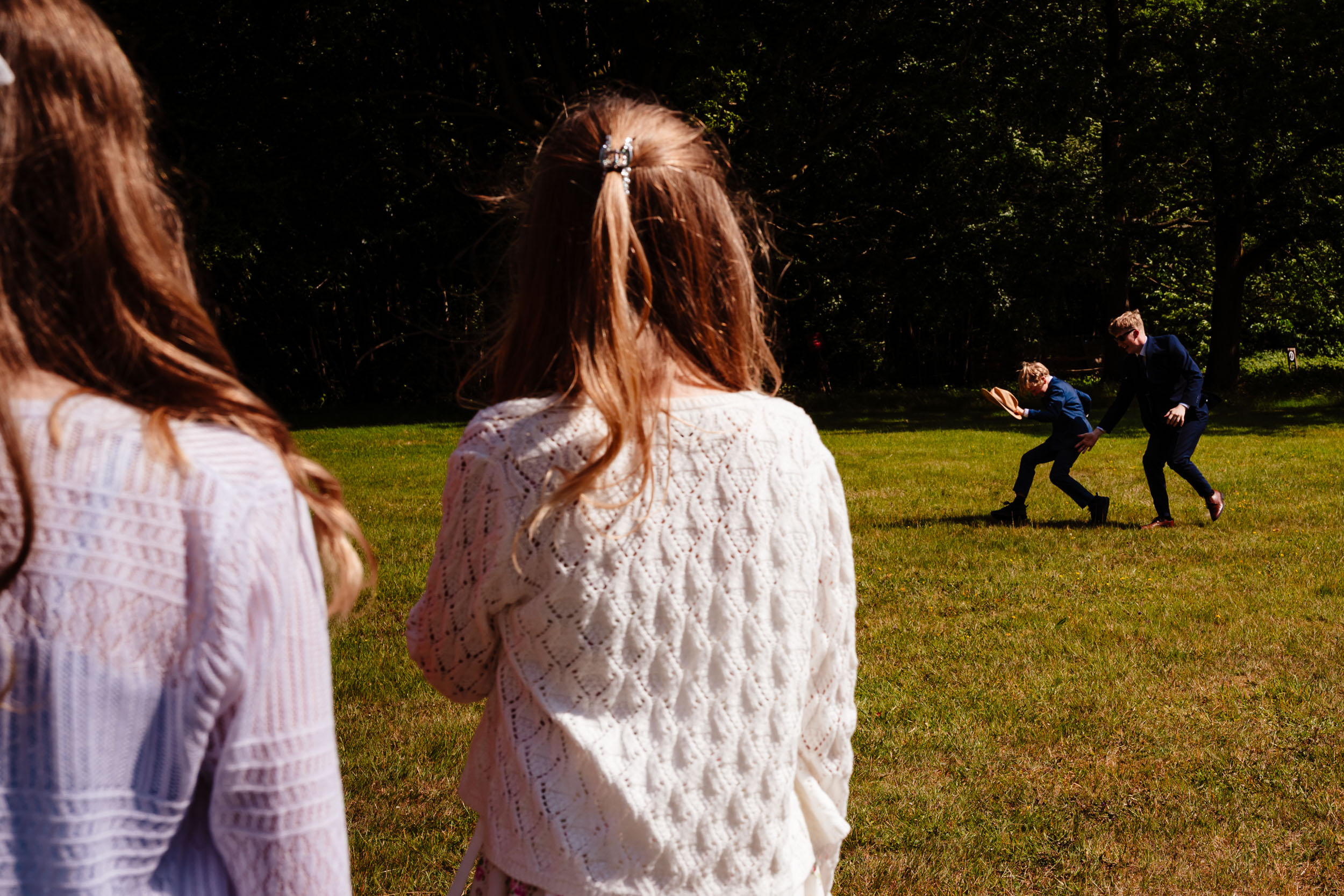 Children chasing a hat while other guests watch and laugh during the reception