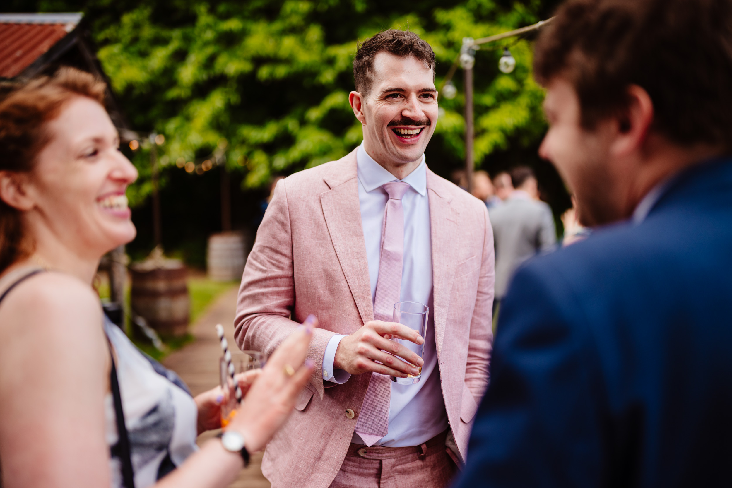 Groom laughing with guests outside during the reception at The Dreys