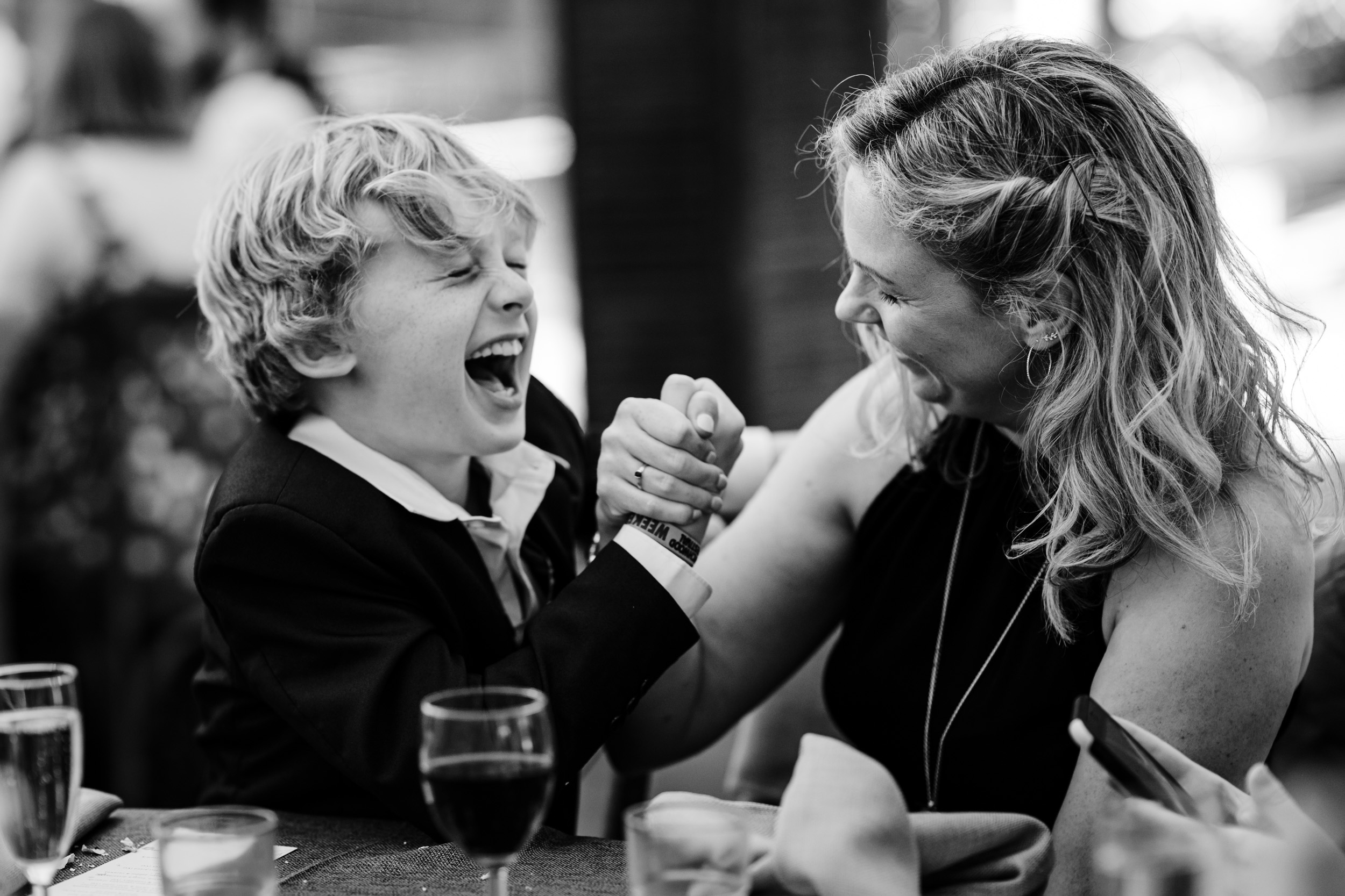 Bride’s sister arm wrestling with a child while both laugh and have fun