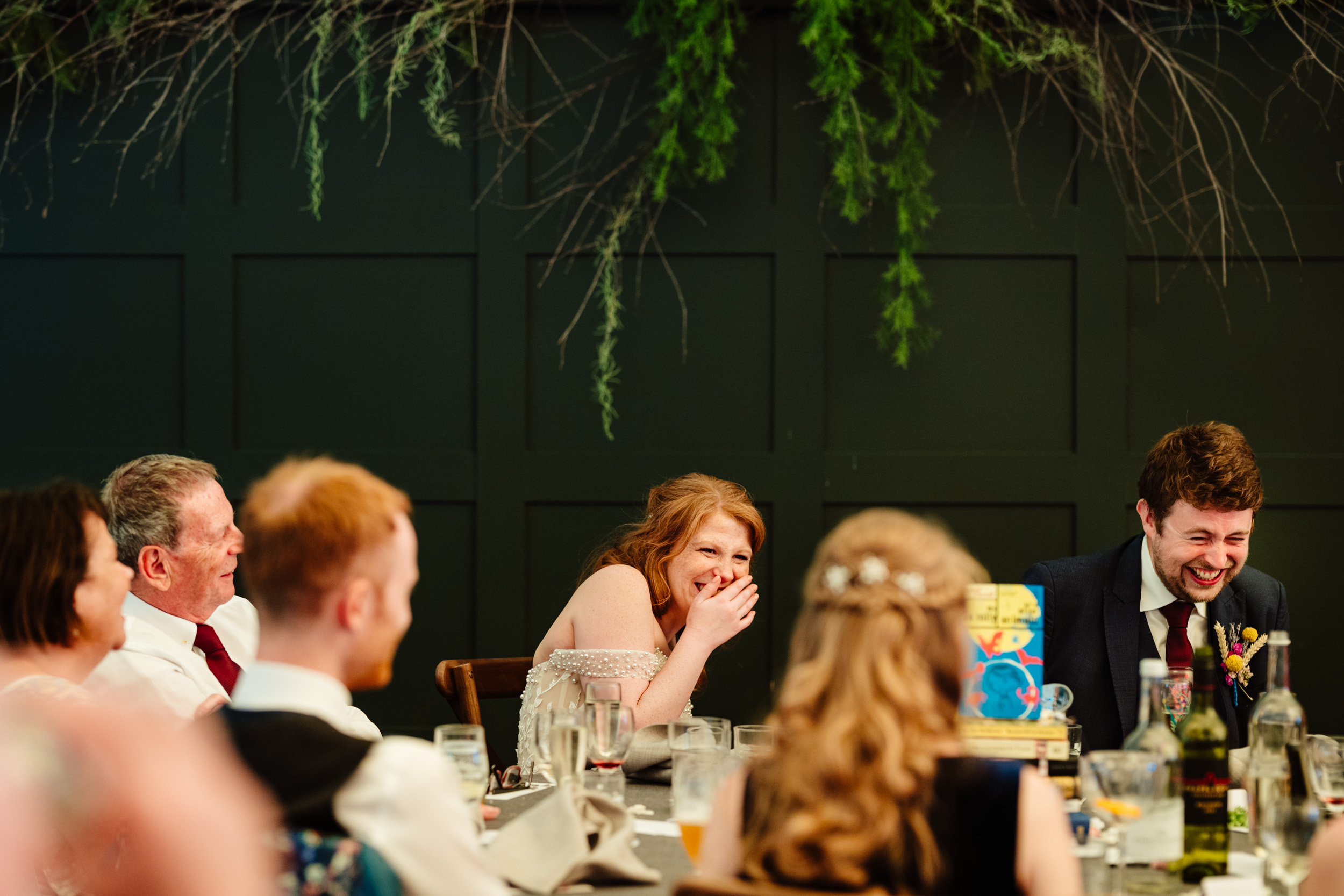 Wide view of the top table with the bride and groom laughing together