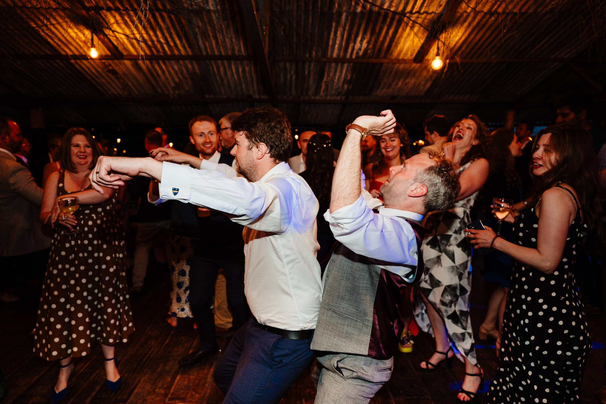 Groom and best man dancing wildly together on the dance floor