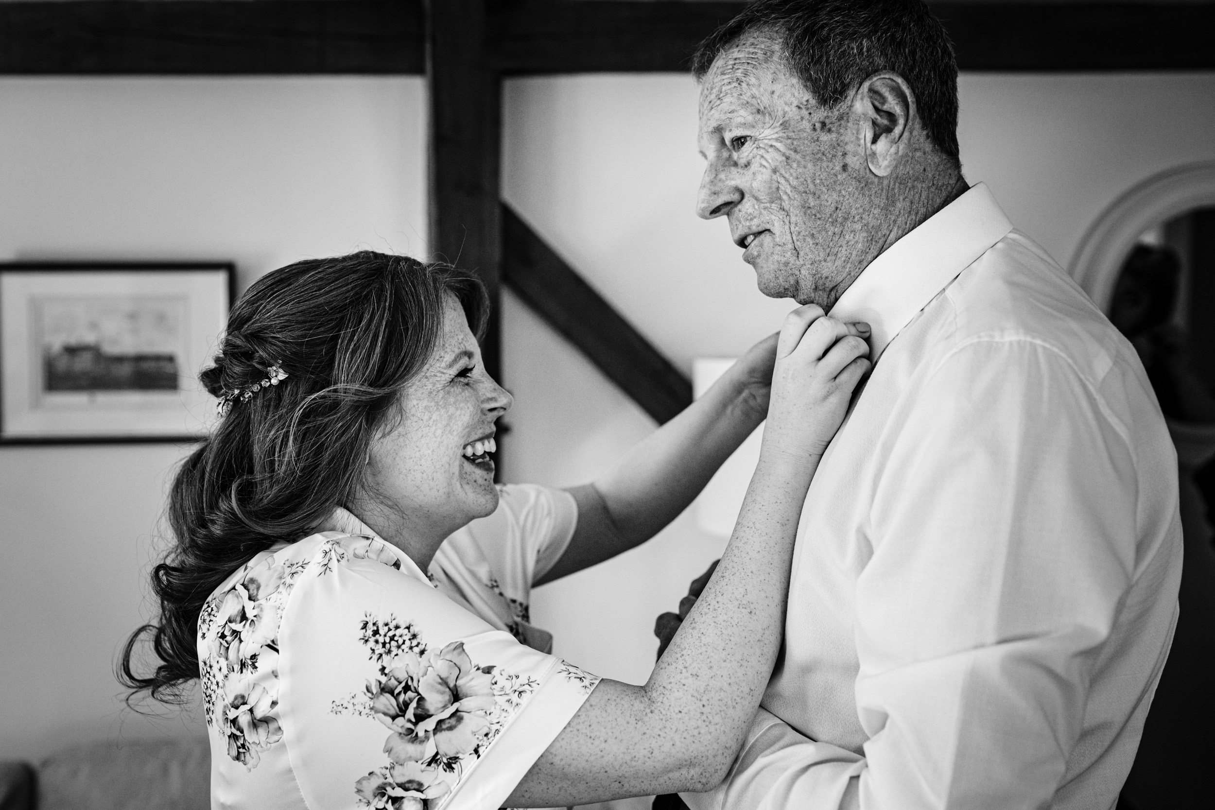 Bride helping her dad fasten the top button of his shirt