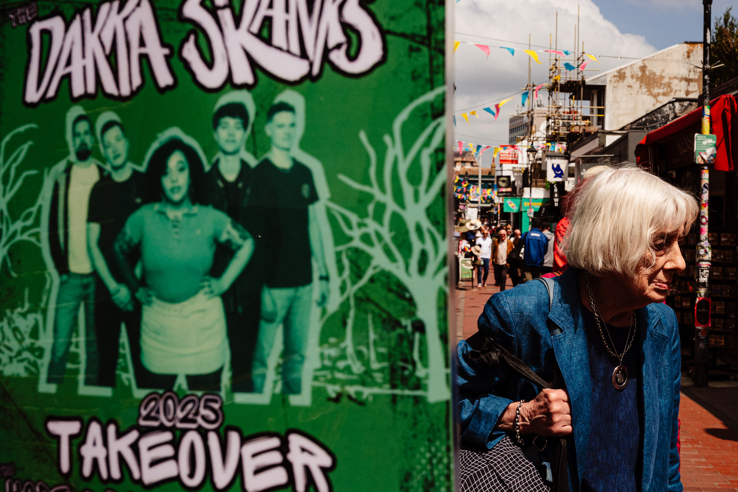 An old lady looks away from a Danka Skanks poster in Brighton.