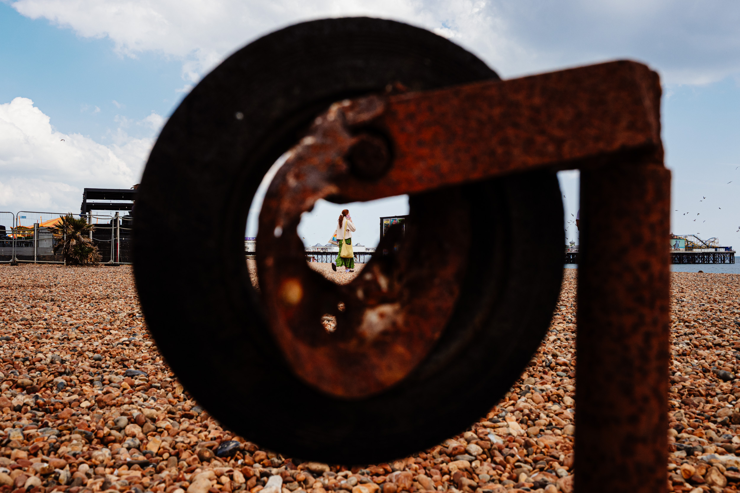 Woman walking down the beach captured through the middle of a rustic wheel.