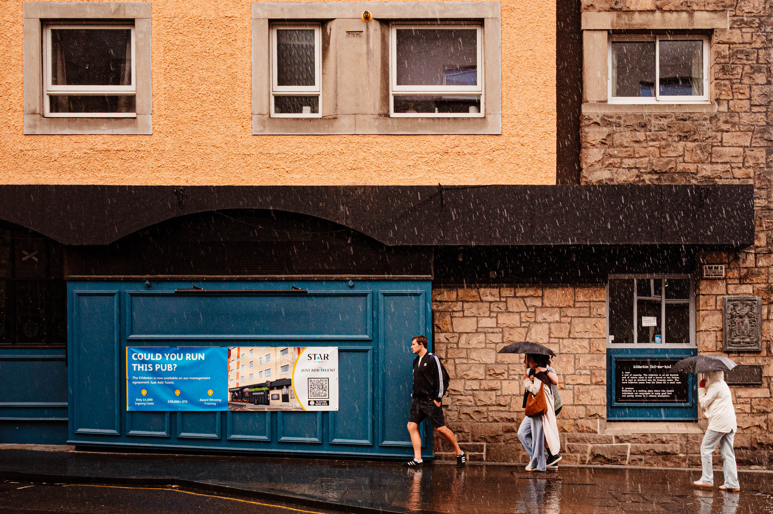 People in the rain walking towards a shelter.