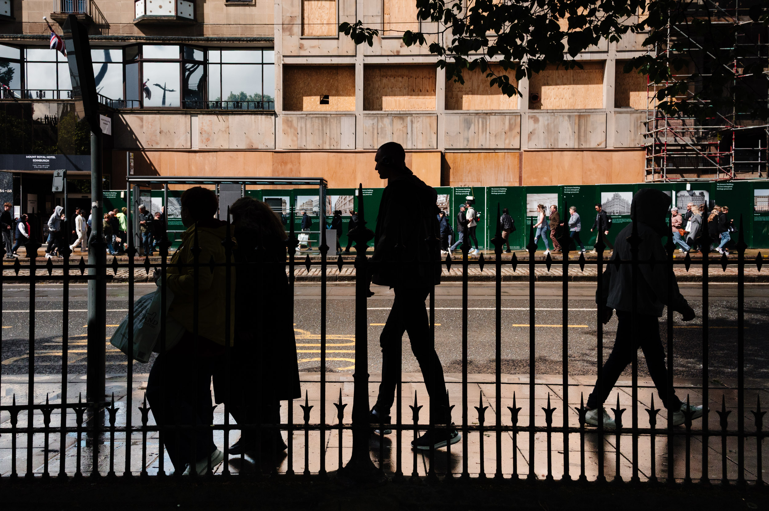 People in shadows walking down th road.