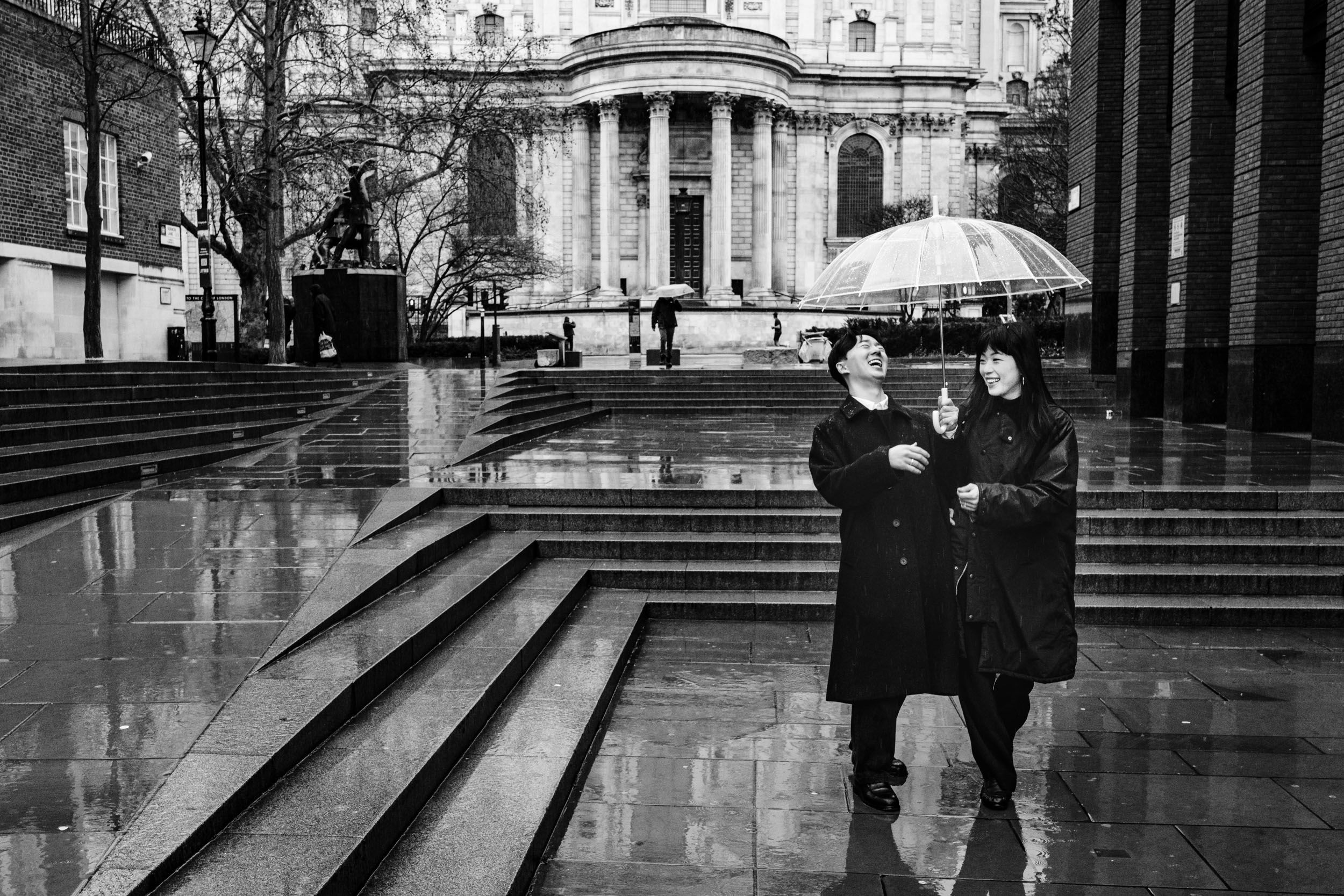 Couple laughing after he nearly slipped during their St Paul’s Cathedral proposal shoot.