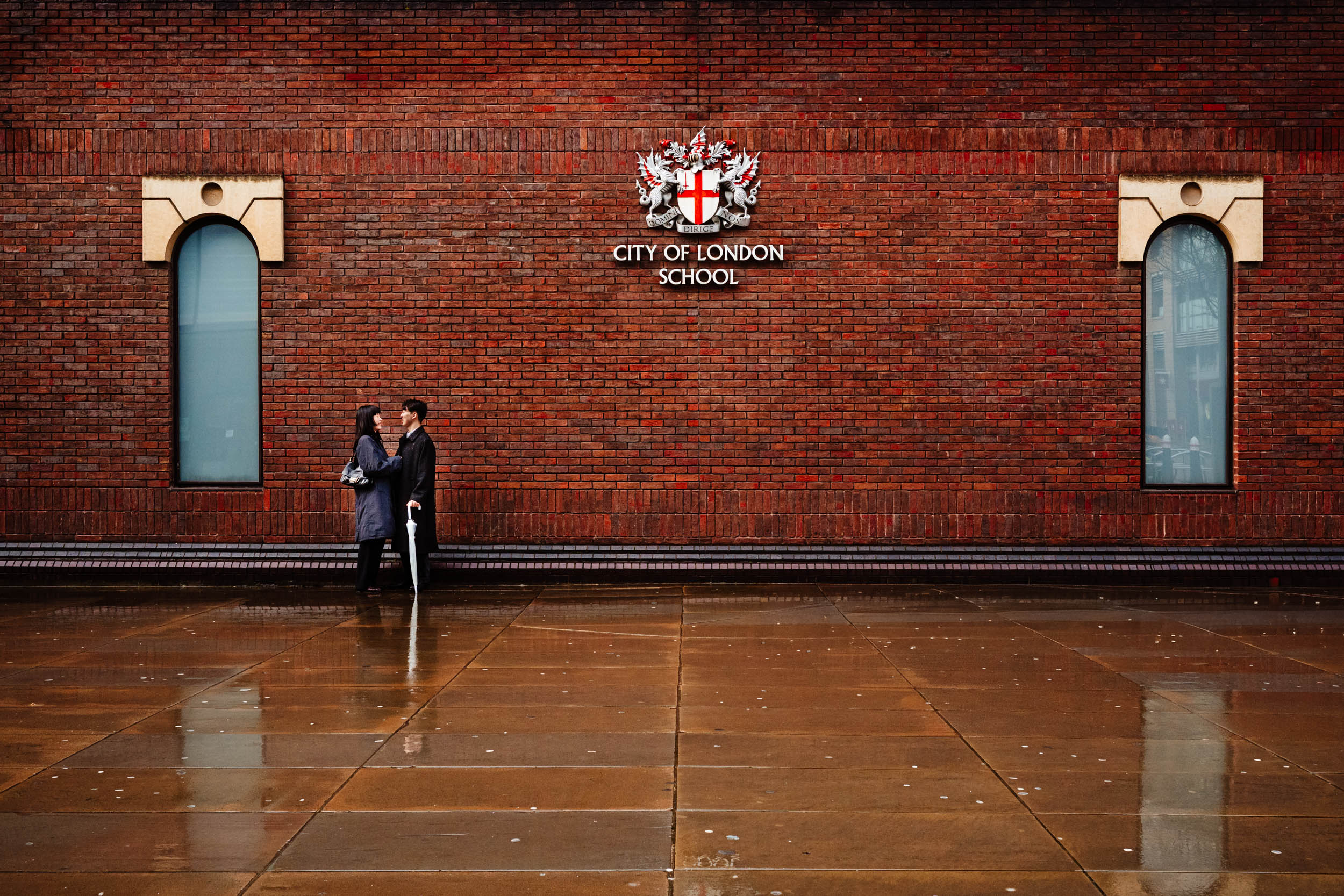 Couple standing by a wall near City of London School after their St Paul’s Cathedral proposal.