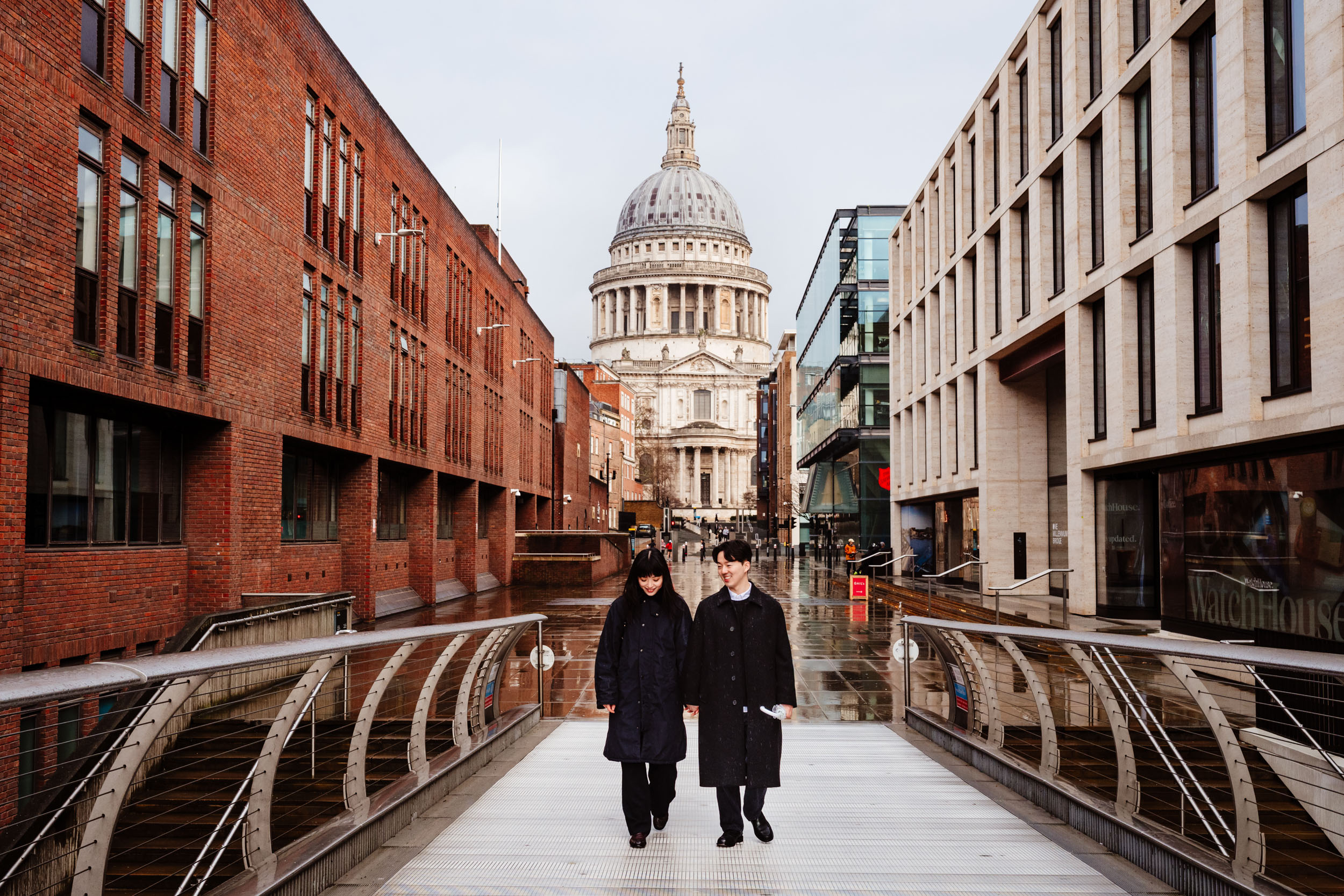 Newly engaged couple walking across Millennium Bridge in London.