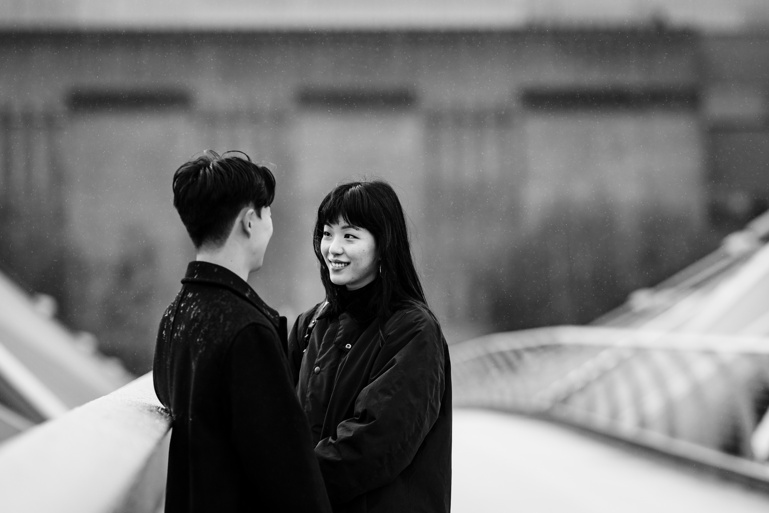 Couple sharing a quiet moment on Millennium Bridge as rain begins to fall.