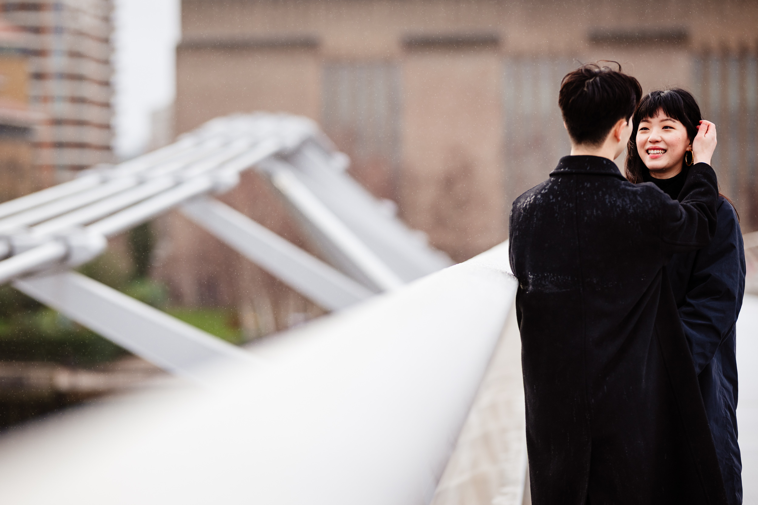 He brushes her hair from her face on Millennium Bridge after the London proposal.