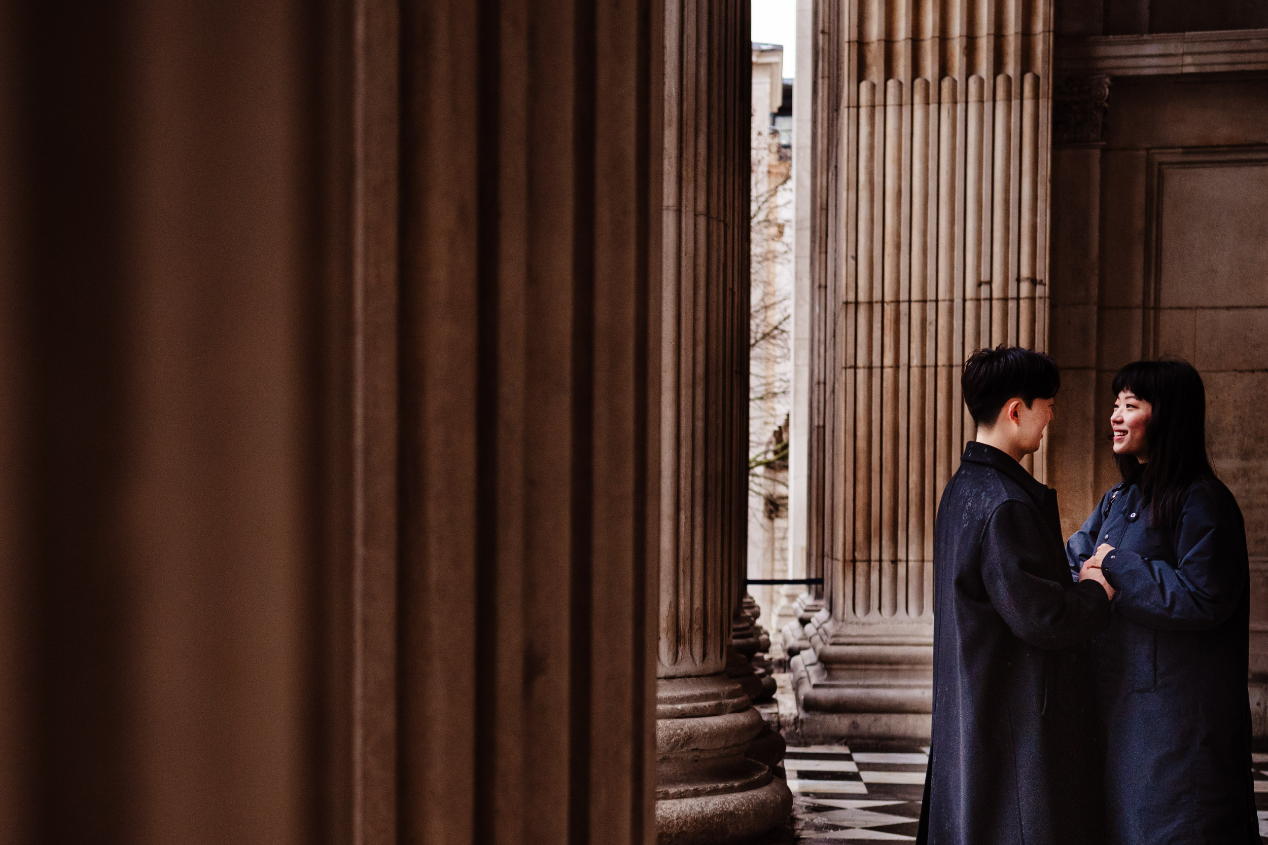 Engaged couple smiling together on the steps of St Paul’s Cathedral.