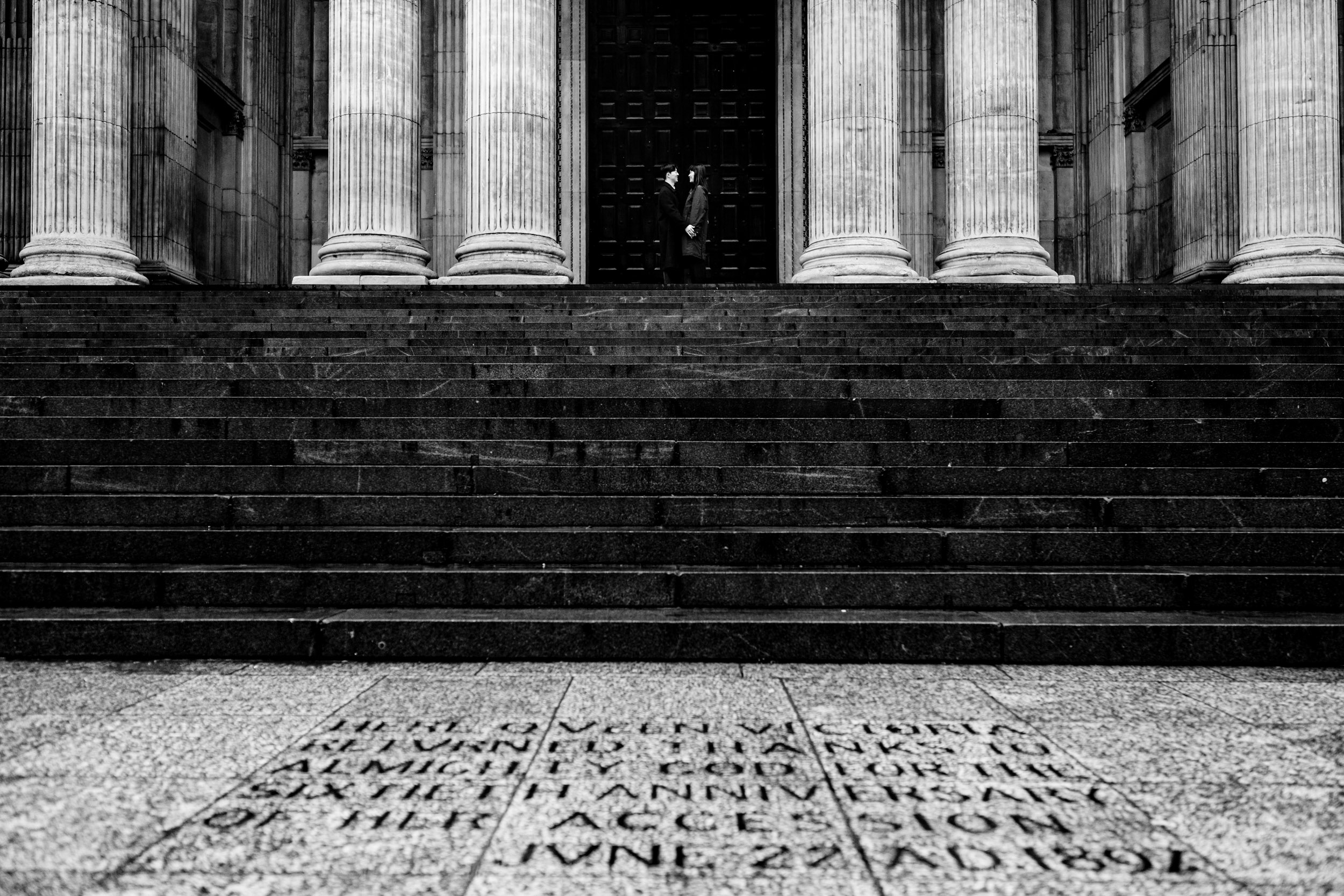 Wide shot of the couple kissing outside St Paul’s Cathedral after their surprise proposal.