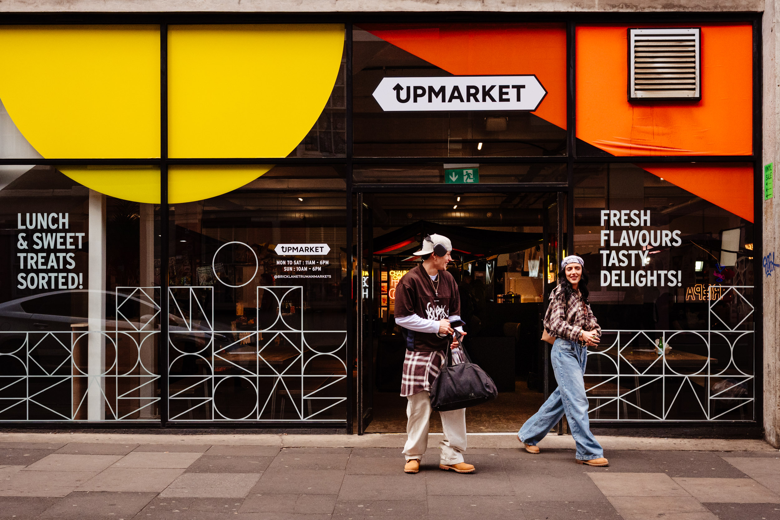 Young couple comes out of a street food market in Shoreditch.
