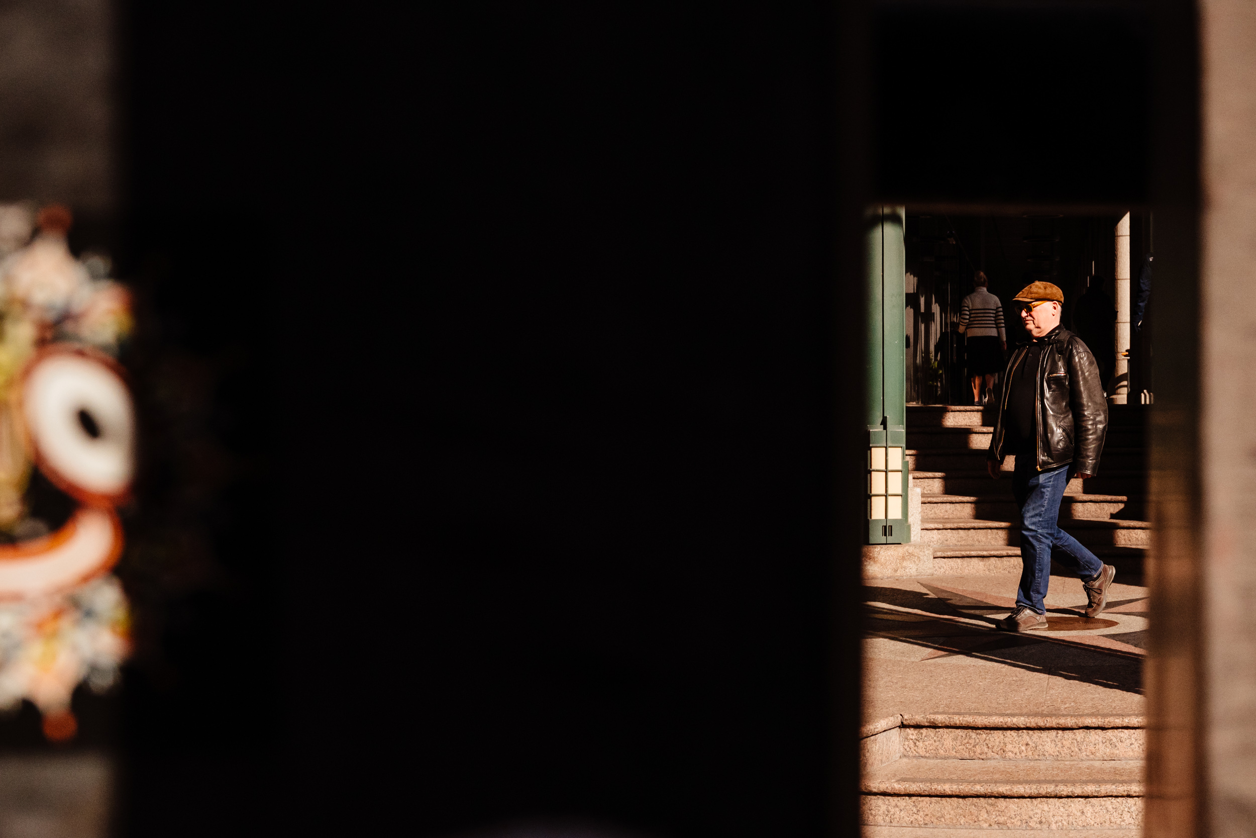 Man walks across the street in the sunlight.