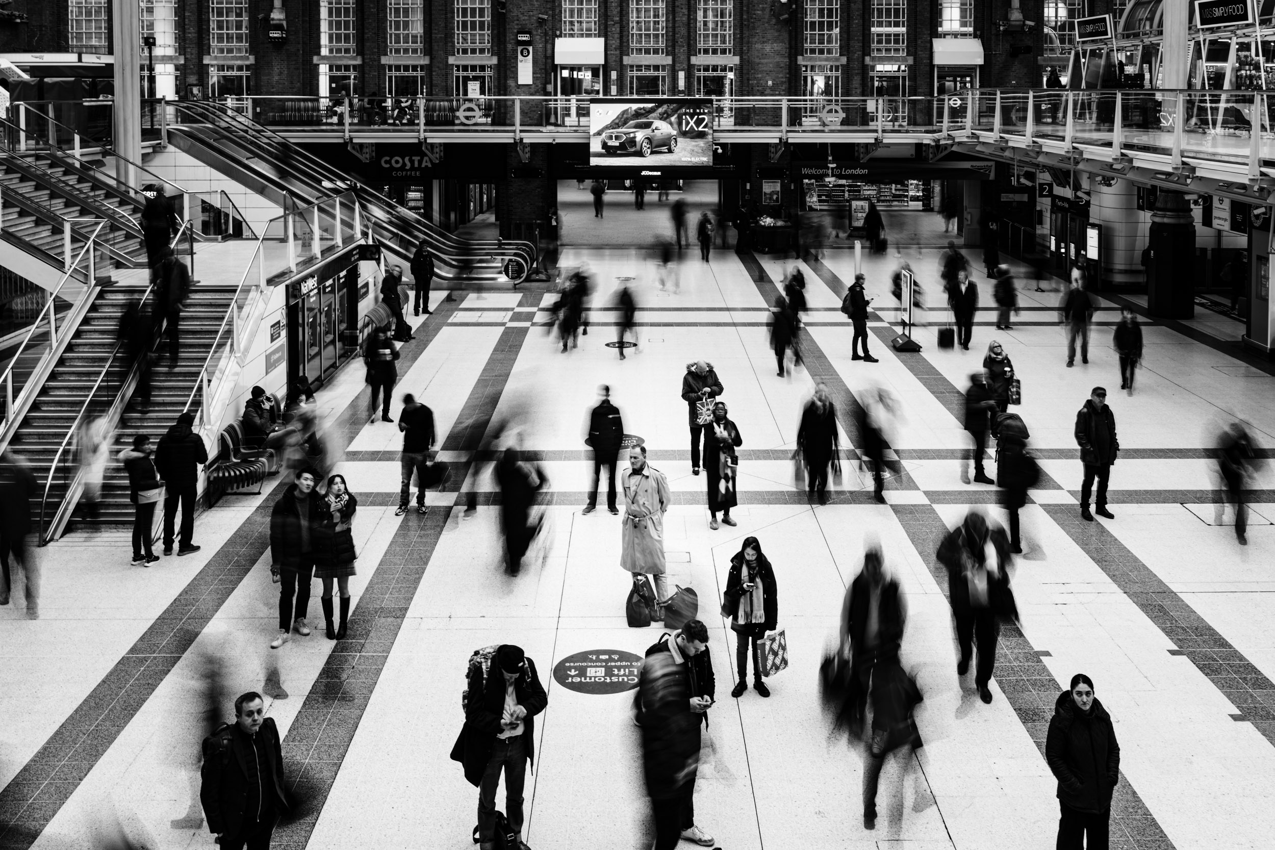 Man waiting still in a busy train station in London.