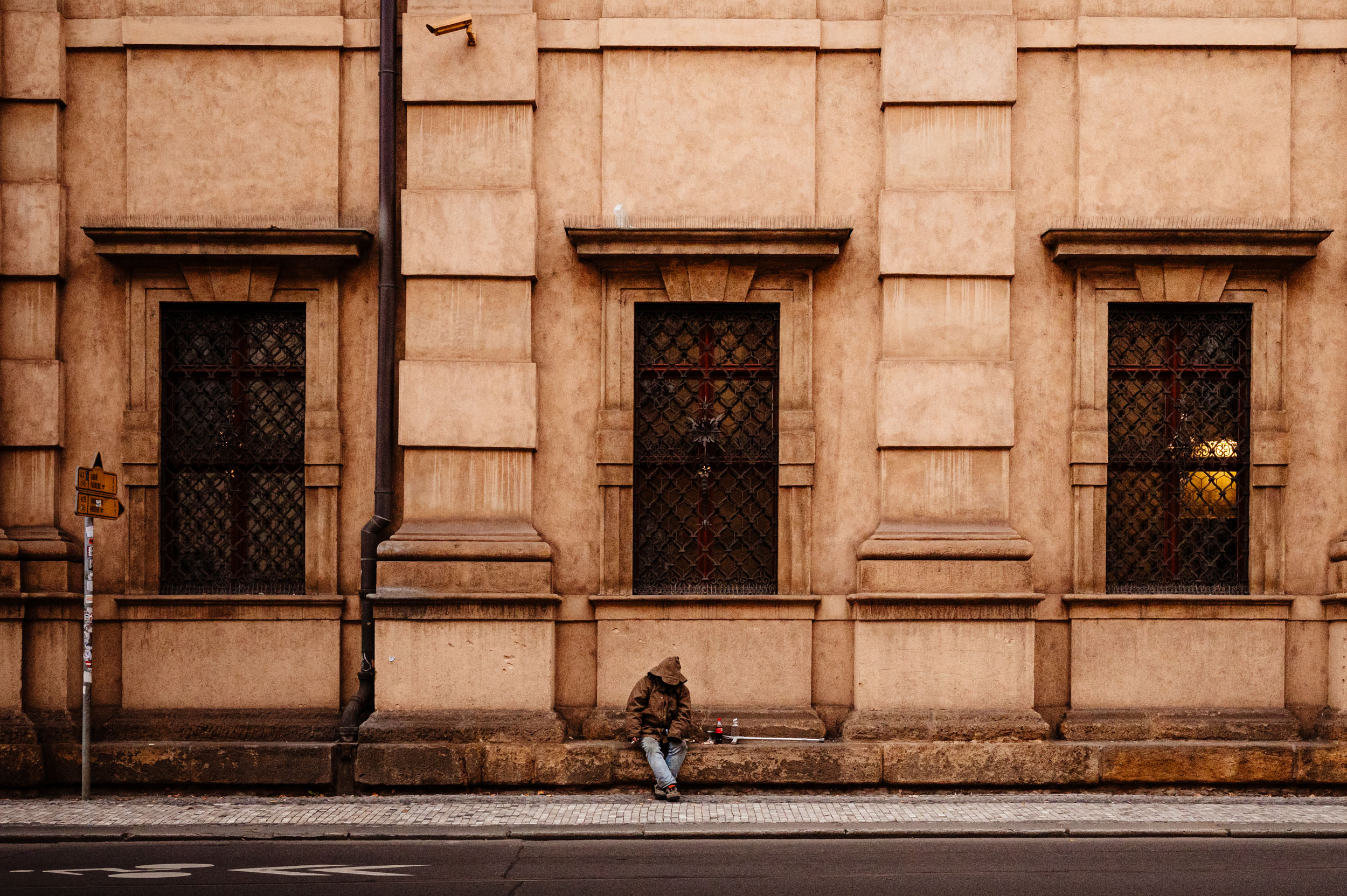 Homeless man leaning against a building wall.