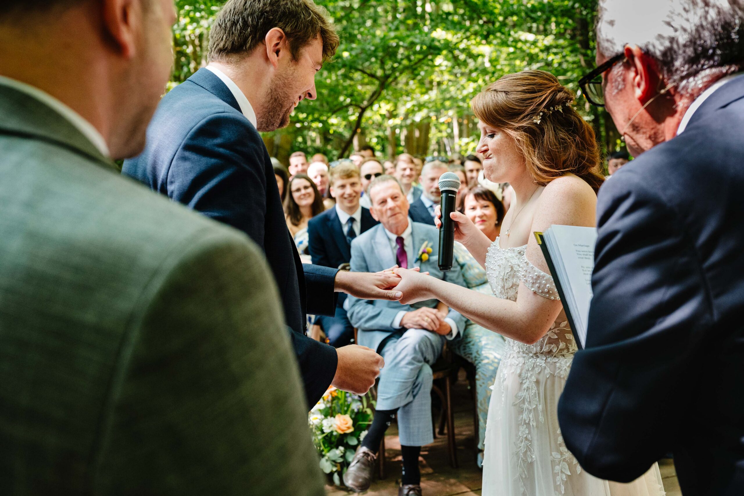 Bride and groom exchanging rings during their woodland wedding ceremony.
