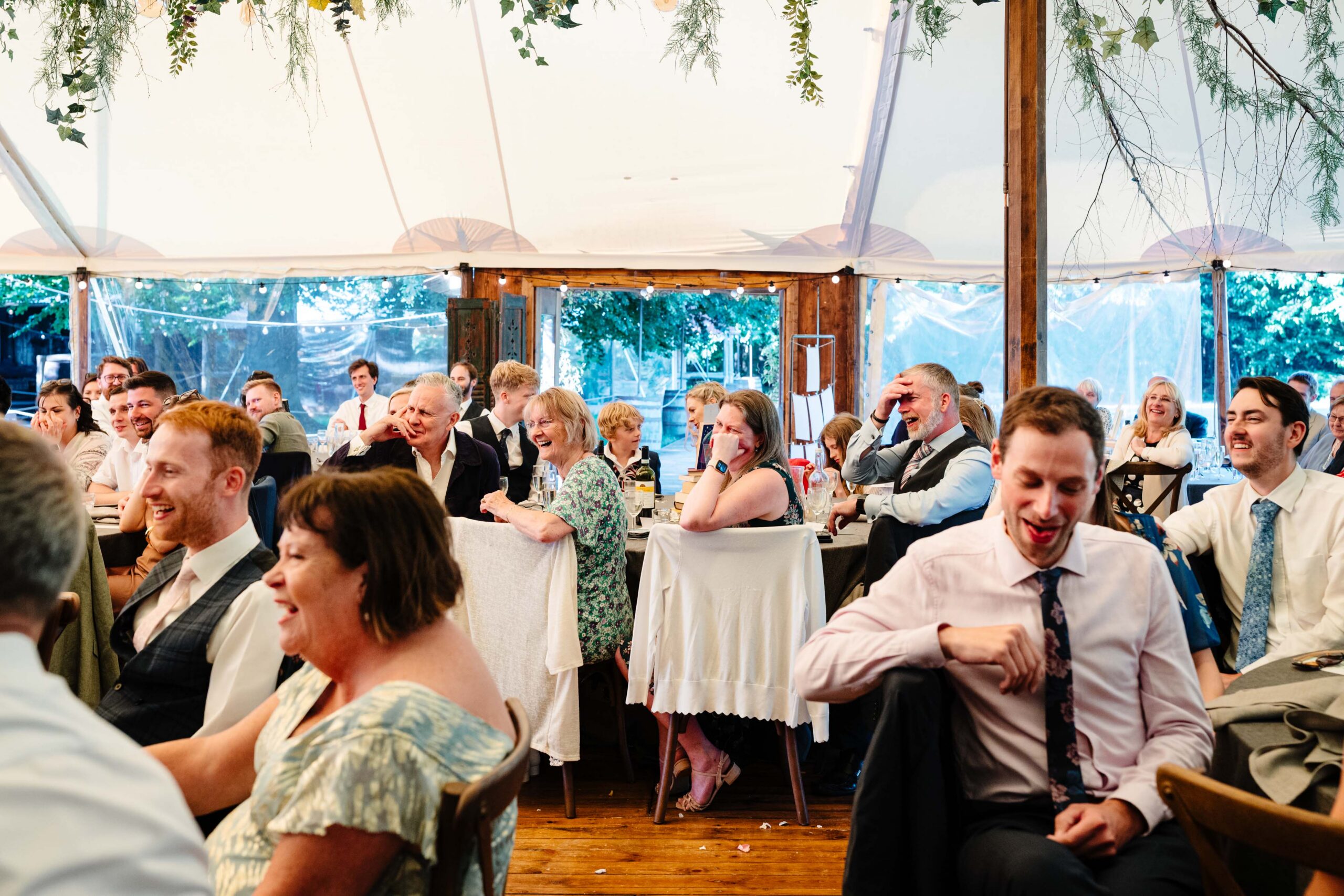 Guests celebrating during lively wedding speeches at The Dreys wedding venue.