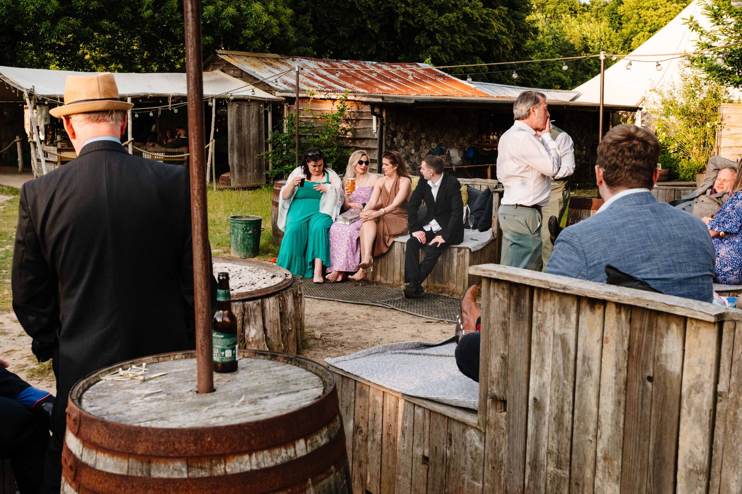 Guests enjoying drinks outside a rustic wedding building at The Dreys.