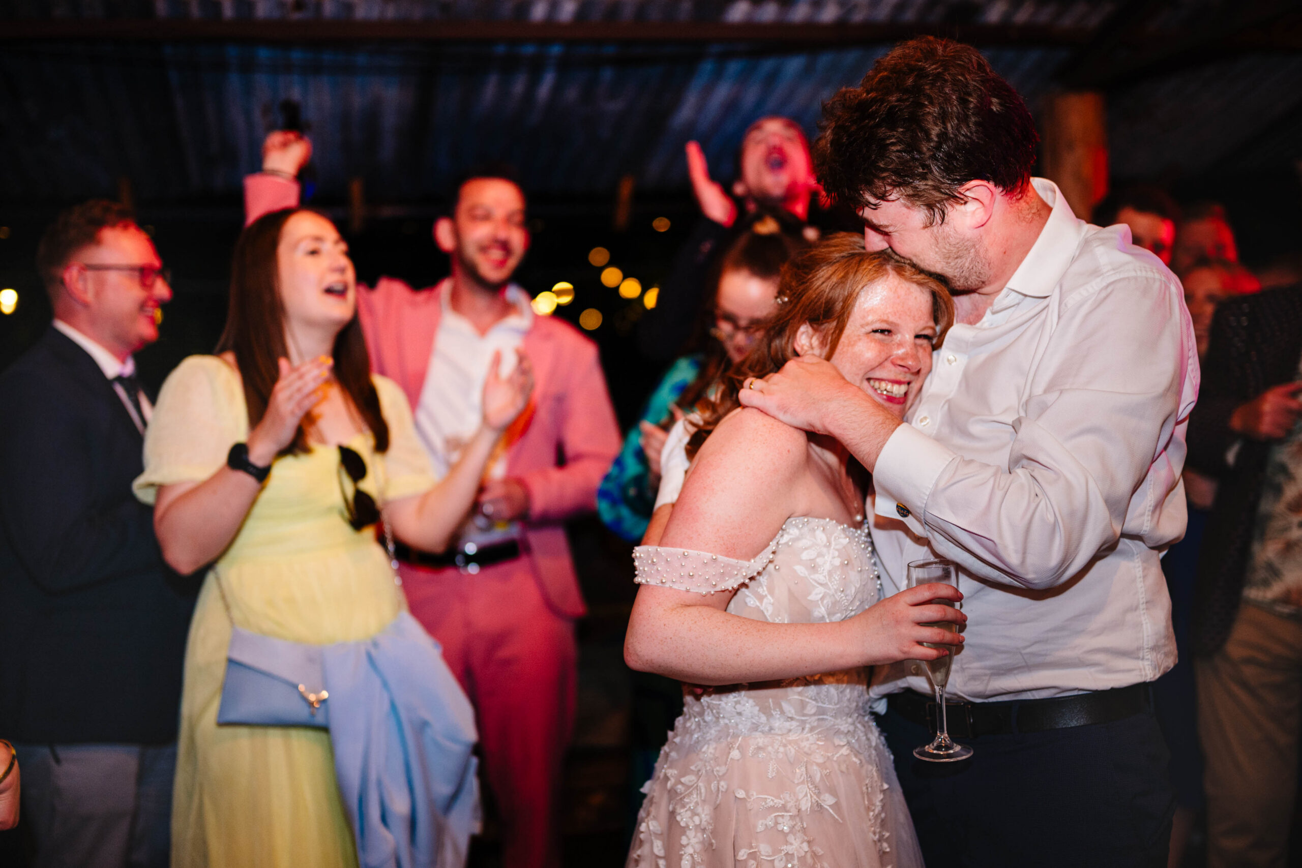 Bride dancing with champagne glass in hand during wedding celebrations at The Dreys.