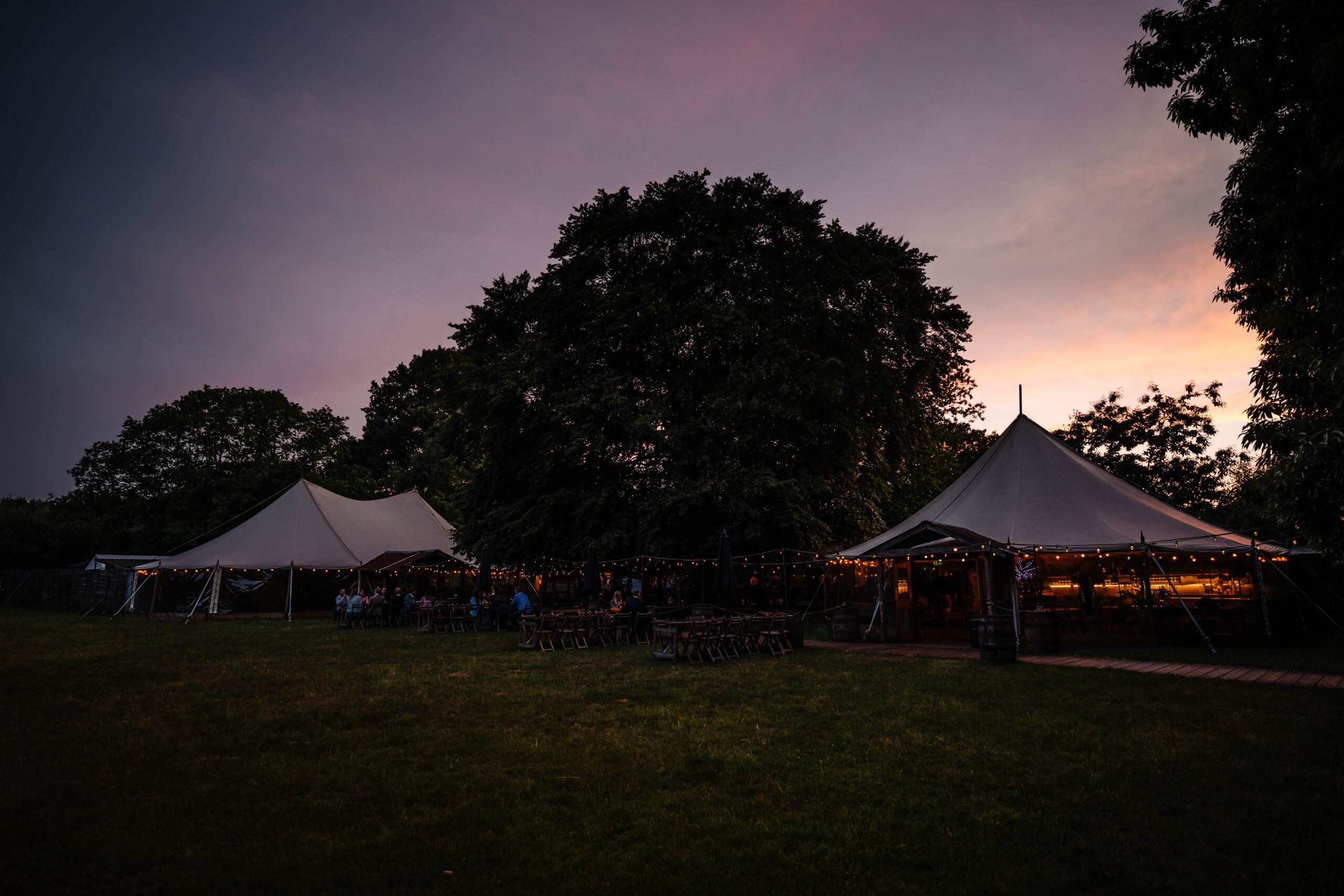 Twilight view of The Dreys wedding venue with illuminated marquees at sunset in Kent.
